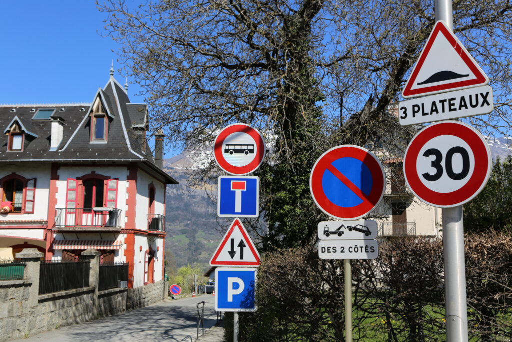 France. Auvergne-Rhône-Alpes. Haute-Savoie. Saint-Gervais-les-Bains. 04/10/2020. This colorful image depicts several road signs: one-way, two-way access, no buses, parking, parking prohibited under penalty of removal of vehicle, speed limit to 30km, speed bump.